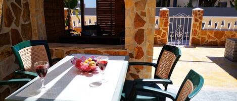 Un patio al aire libre con un arco de piedra, una mesa con sillas y un frutero.