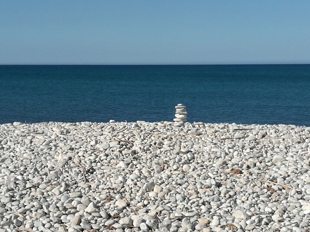 A pebble beach with a stack of stones in the center.