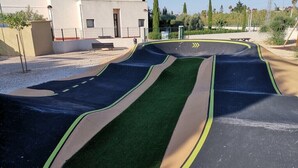 Un'area giochi con una pista curva e manto in erba sintetica.