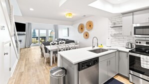 Cocina moderna con lavavajillas, fregadero y estufa. Cuenta con un comedor con mesa y sillas.