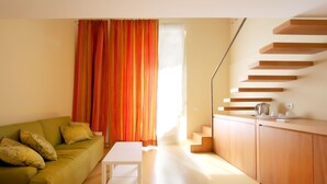 A modern living room with a green sofa, white coffee table, and a staircase leading to a kitchen area. - Pretaloger Verdi 18 Studio Classic (NAPOLI)