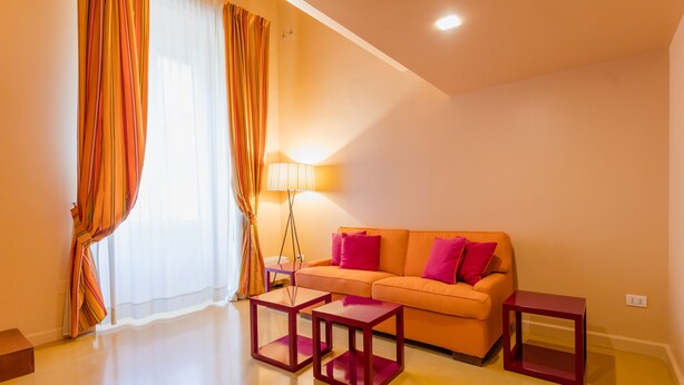 A modern living room with a sofa, two side tables, and a floor lamp. - Pretaloger Verdi 18 Studio Classic (NAPOLI)