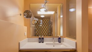 A bathroom with a white sink, two bottles of shampoo, a mirror, and a shower with a checkered tile wall. - Pretaloger Verdi 18 Studio Classic (NAPOLI)
