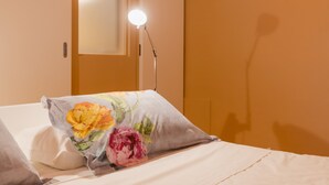A bed with a floral pillow, a bedside lamp, and a door with a light. - Pretaloger Verdi 18 Studio Classic (NAPOLI)