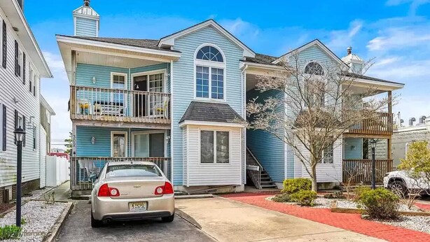 A two-story residential building with a balcony on the upper floor, a front porch, and a garage. - Close to everything! Short walk to beach, boardwalk and restaurants (Wildwood)