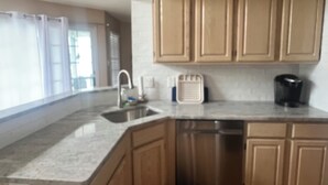 A kitchen with wooden cabinets, a stainless steel sink, a dishwasher, and a coffee maker. - Close to everything! Short walk to beach, boardwalk and restaurants (Wildwood)