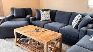 A modern living room with a sectional sofa, a wooden coffee table, and a round mirror on the wall. - Close to everything! Short walk to beach, boardwalk and restaurants (Wildwood)
