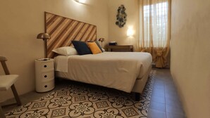 A bedroom with a bed, bedside tables, a lamp, a wall-mounted decoration, and a window with curtains. - Lo Strullo - Ground Floor Suite (Pisa)