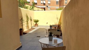 A narrow courtyard with a tiled floor, potted plants, and outdoor seating. - Lo Strullo - Ground Floor Suite (Pisa)