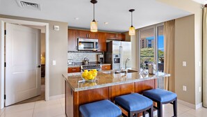 Una cocina moderna con armarios de madera, encimera de granito y una isla central con taburetes de bar.