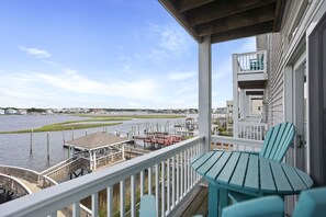 Un balcon avec vue sur un port de plaisance, un quai et un petit kiosque.
