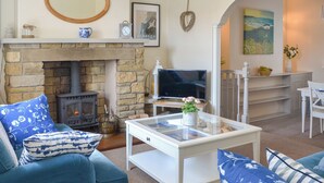 A living room with a stone fireplace, a television, and a dining area with a white table and chairs. - Great sea views, close to a small beach and Flamborough Head lighthouse. (Flamborough)