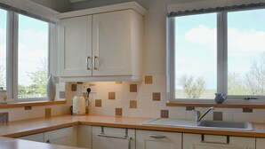 A modern kitchen with white cabinets, a wooden countertop, and a window with a view of trees. - Great sea views, close to a small beach and Flamborough Head lighthouse. (Flamborough)