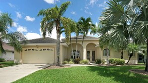 A two-story house with a garage, palm trees, and a well-maintained lawn. - Contemporary waterfront pool home with Gulf access (CAPE CORAL)