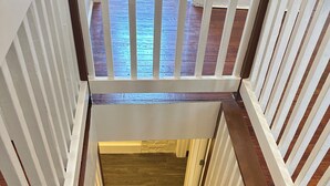 Una escalera de madera con barandillas blancas que da a una plataforma.
