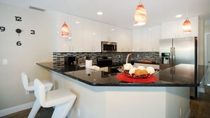 A modern kitchen with white cabinets, stainless steel appliances, and a central island with a red placemat. - Waterfront home with a Billiard table pool and spa (CAPE CORAL)