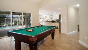 A pool table in a spacious room with a view of a pool outside. - Waterfront home with a Billiard table pool and spa (CAPE CORAL)