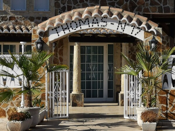 A stone building entrance with a sign reading "THOMAS-MY" and two gates leading to a door.