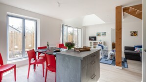 Une cuisine moderne avec un îlot central, des chaises rouges et de grandes fenêtres.