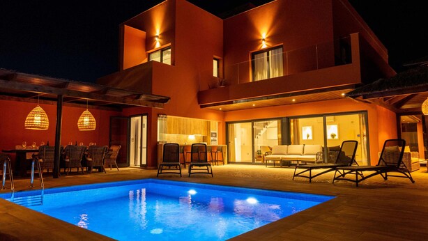 A modern two-story building with a swimming pool, outdoor seating, and a well-lit interior. - Villa Privada de Lujo con Piscina, Villa Sabi Sabi (Corralejo Playa)