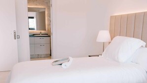 A hotel room with two beds, a bathroom visible through an open door, a bedside lamp, and a book on one bed. - Villa Privada de Lujo con Piscina, Villa Sabi Sabi (Corralejo Playa)