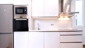 A modern kitchen with stainless steel appliances, white cabinetry, and a built-in oven. - Genteel Home Recaredo VII (Seville)