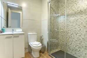 Ein modernes Badezimmer mit Toilette, Waschbecken und Duschkabine aus Glas.