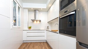 Et moderne køkken med hvide skabe, en rustfri emhætte og en indbygget ovn.