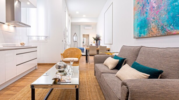 Een moderne woonkamer met een bank, salontafel en een eethoek op de achtergrond.