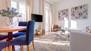 Una sala de estar moderna con una mesa de comedor de madera, sillas azules, un sofá color beige y una mesa de centro.