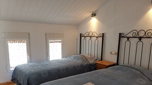 A bedroom with two beds, a wooden floor, a window with a curtain, and a wall-mounted light fixture. - Terraced apartment André A3 by the sea (Els Poblets, Comunidad Valenciana)