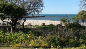 A beach with rocky shore, trees, and clear blue sky. - Terraced apartment André A3 by the sea (Els Poblets, Comunidad Valenciana)
