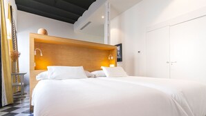 Hotellihuone, jossa on suuri sänky, puinen pääty, kaksi yöpöytävalaisinta ja vaatekaappi.