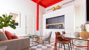 Un salon moderne avec un sol à carreaux, un canapé, une table basse et un coin repas comprenant des chaises et une table en verre.