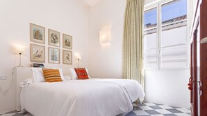 Ein Hotelzimmer mit Bett, einem Fenster mit Vorhängen und Wandbildern.
