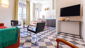 Ein modernes Wohnzimmer mit Schachbrettfußboden, einer Couch, einem Couchtisch und einem an der Wand befestigten Fernseher.