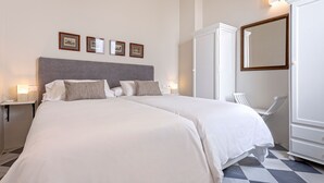 A hotel room with a large bed, a wardrobe, a mirror, and framed pictures on the wall. - Genteel Home San Laureano VI (Seville)