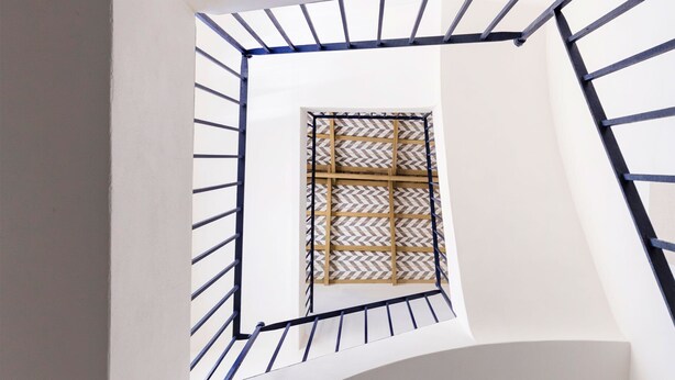 A view of a white staircase with a metal railing leading to a window with a geometric pattern. - Genteel Home San Laureano VI (Seville)