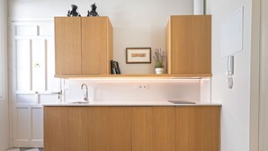 A modern kitchen with wooden cabinets, a white countertop, and a checkered floor. - Genteel Home San Laureano VI (Seville)