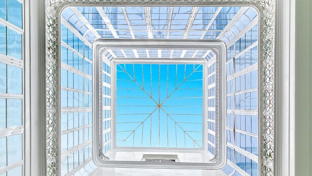 Ein Zimmer mit einem großen Oberlicht, weißen Wänden und einem gemusterten Boden.