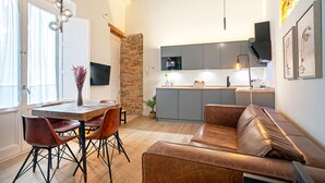 Eine moderne Küche mit grauen Schränken, einem eingebauten Ofen und einem Essbereich mit einem Holztisch und Ledersesseln.