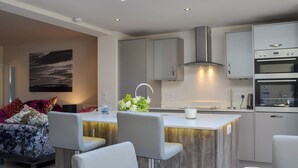 A modern kitchen with a skylight, white cabinets, and stainless steel appliances.