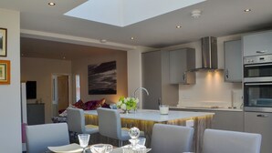 A modern kitchen with a central island, stainless steel appliances, and a dining area with a table set for four.