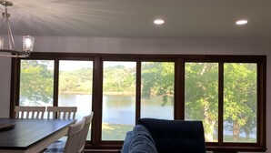 Ein Zimmer mit großem Fenster mit Seeblick, einem Esstisch mit Stühlen und einem Sofa.