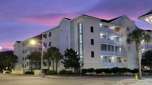 A multi-story hotel with a prominent vertical sign, balconies, and a street view.