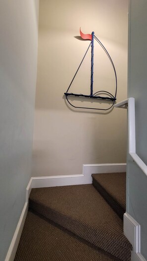 A staircase with carpeted steps and a wall-mounted metal rack.