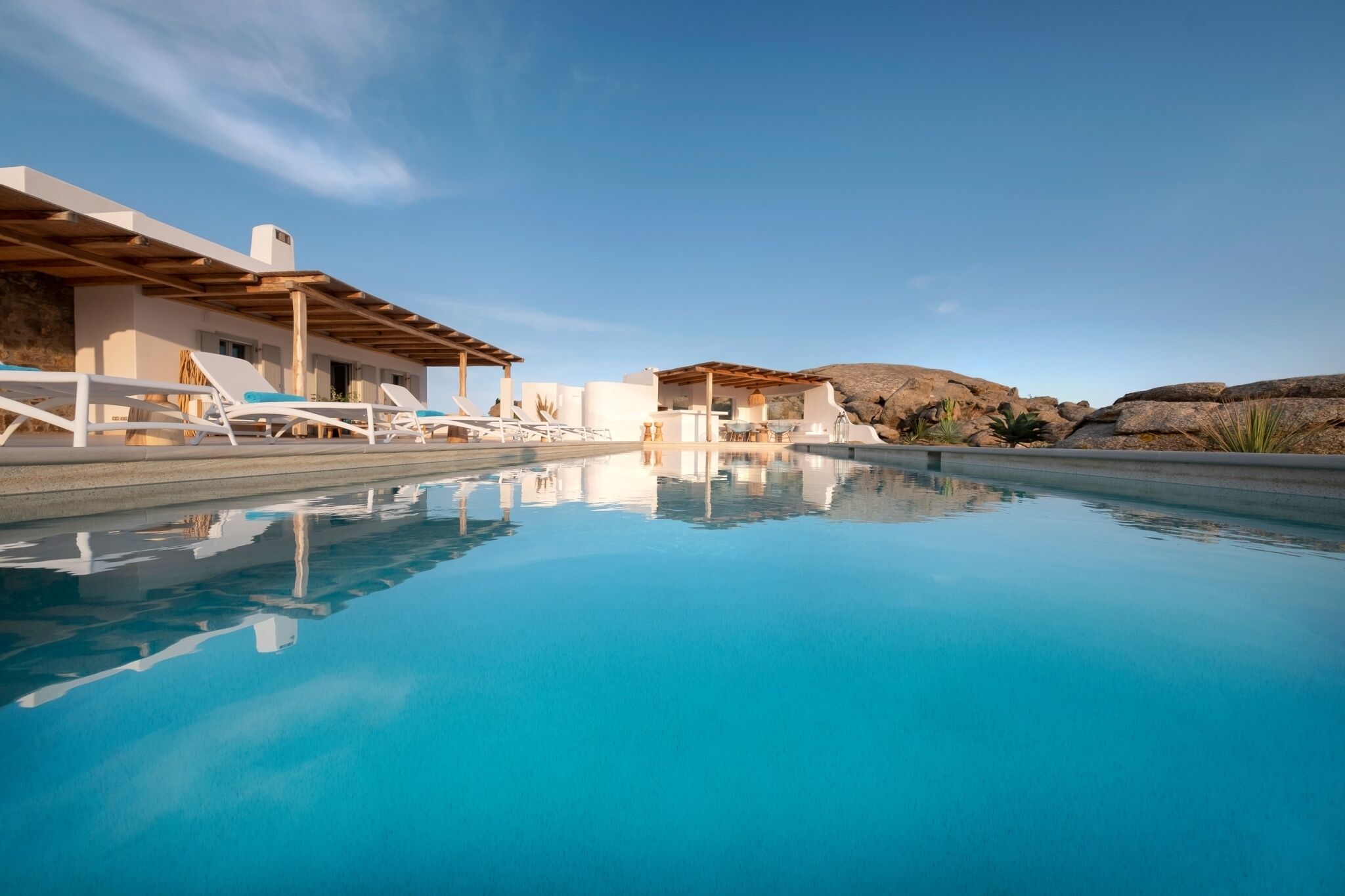 Un espace piscine avec des chaises longues et un bâtiment doté d’un toit plat.