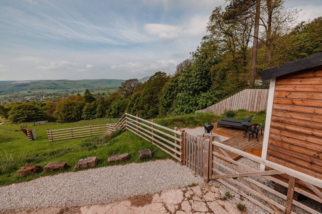 A wooden deck with a view of a valley, a barbecue grill, and a seating area.