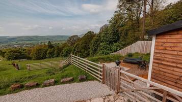 A wooden deck with a view of a valley, a barbecue grill, and a seating area.