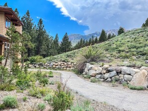 A house with a stone wall and a driveway leading to a mountain path. - Juniper Crest 1 Private and Modern, Mountain Views, Walk to Eagle Lodge by RedAwning (Mammoth Lakes)